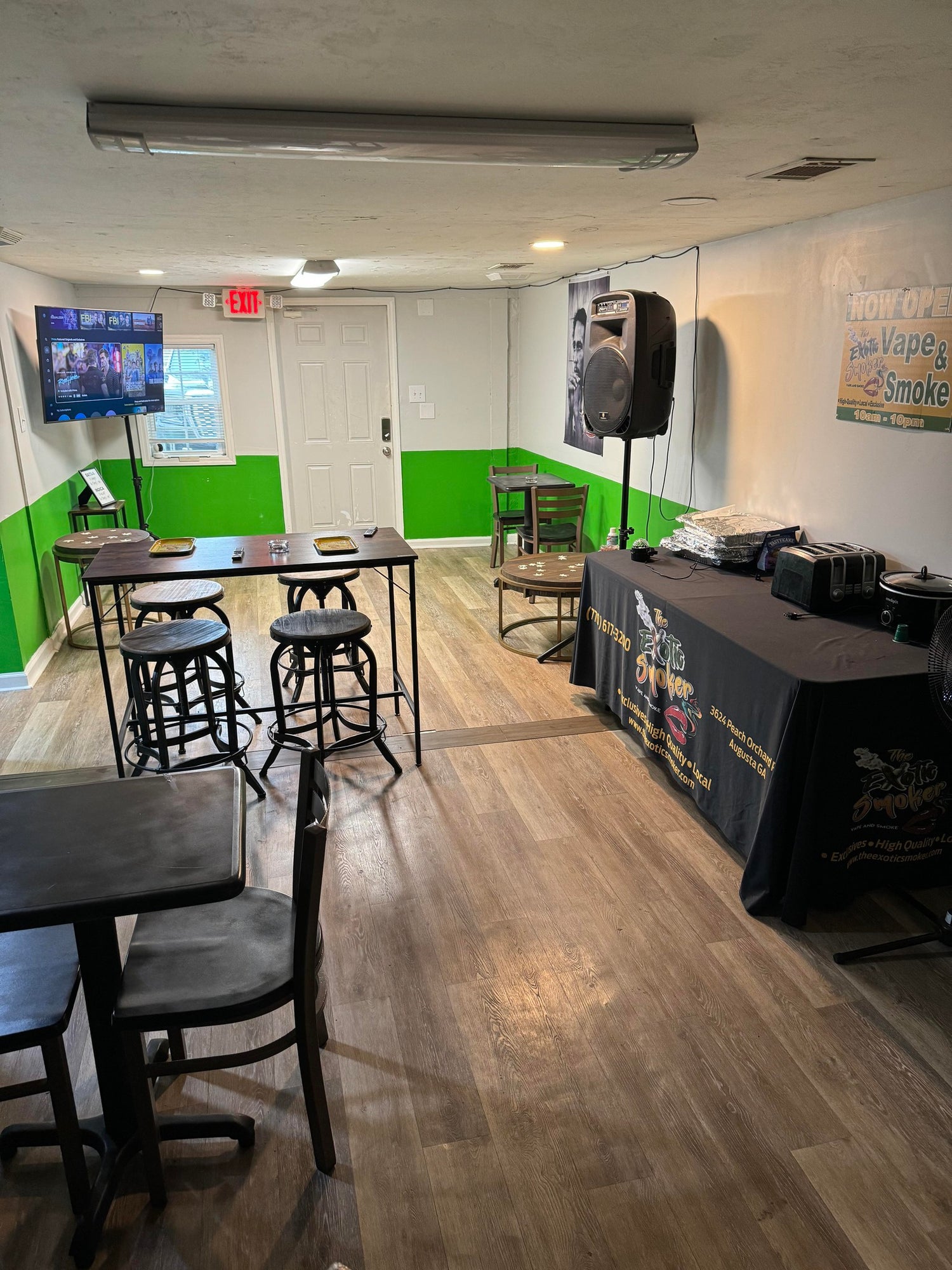 The Exotic Smoker Vape and Smoke Shop - Rental Venue 3 - tables and chairs in a white and green building with a big tv and a table with sound system